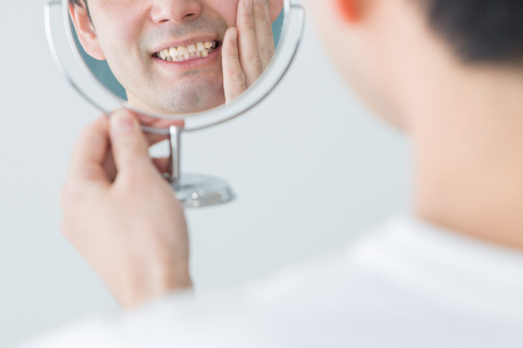 鏡で自分の歯を見ている男性
