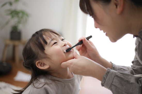 仕上げ磨きする母親と子供