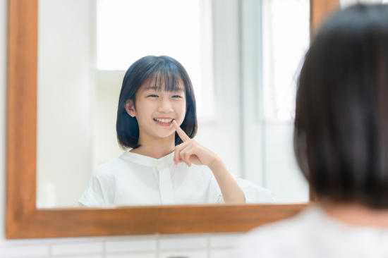 矯正で綺麗になった歯並びを鏡で確認する女の子