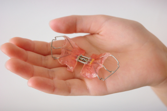 床矯正の装置を持つ子供の手