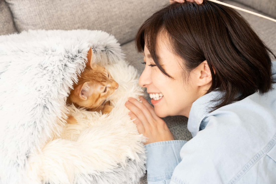 マウスピース矯正で整った歯並びになった笑顔の女性が愛猫と戯れているイメージ