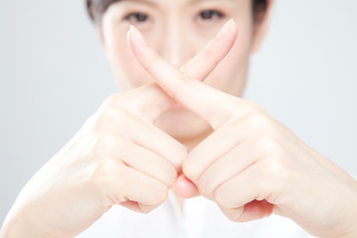インビザラインが向かないと指でバツマークを作る女性